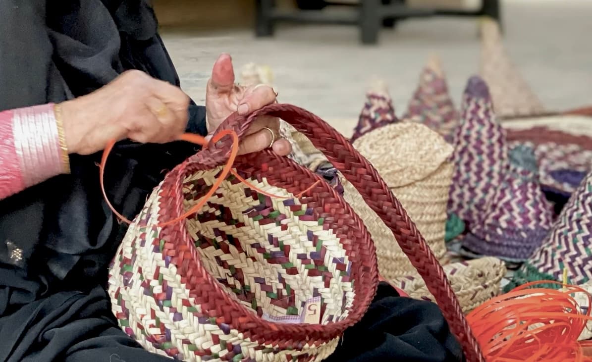 Mains d'artisane tressant un panier d'osier